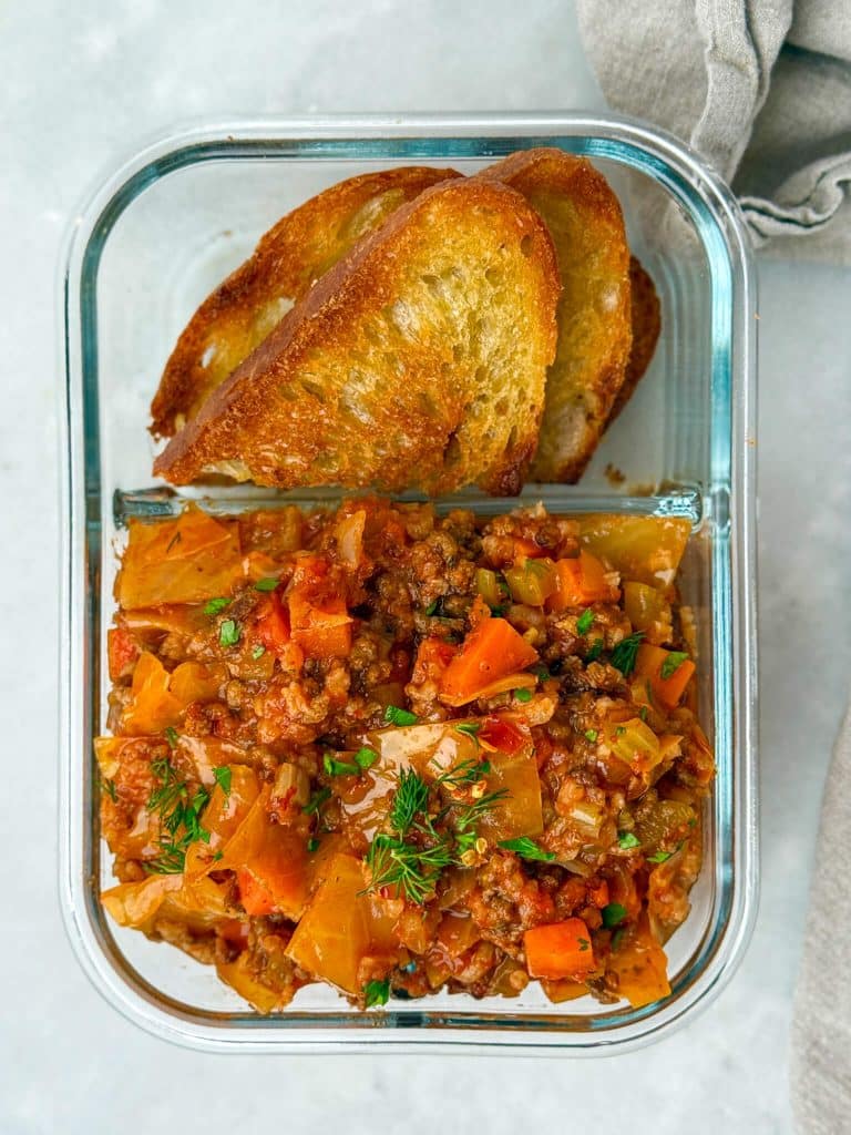 Meal prep container with unstuffed cabbage soup and toasted bread for easy high-protein lunches