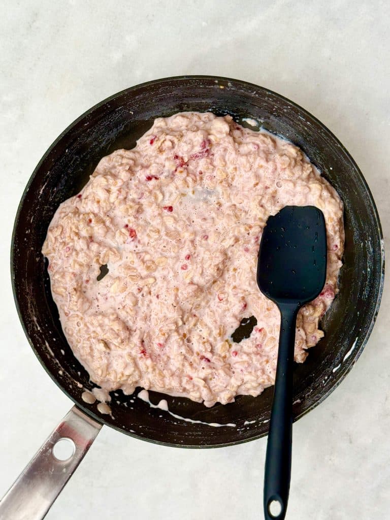 Creamy protein oatmeal base cooked on the stovetop, ready to be topped with peanut butter and jam.