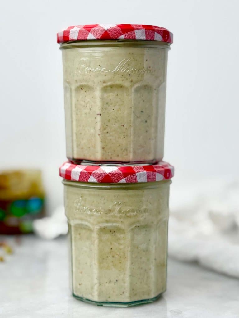High-protein pistachio overnight oats in glass jars, prepped for meal prep and stacked on a white marble surface