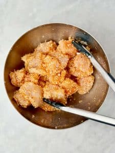 Chicken breast pieces coated in seasoned panko before air frying.