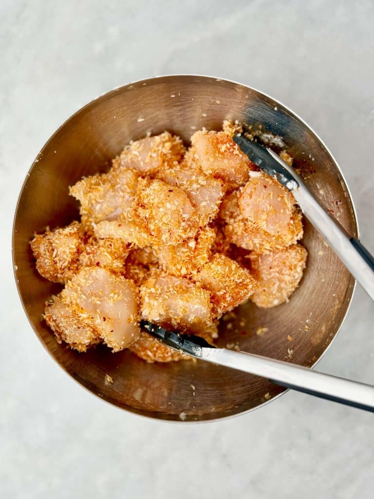 Chicken breast pieces coated in seasoned panko before air frying.