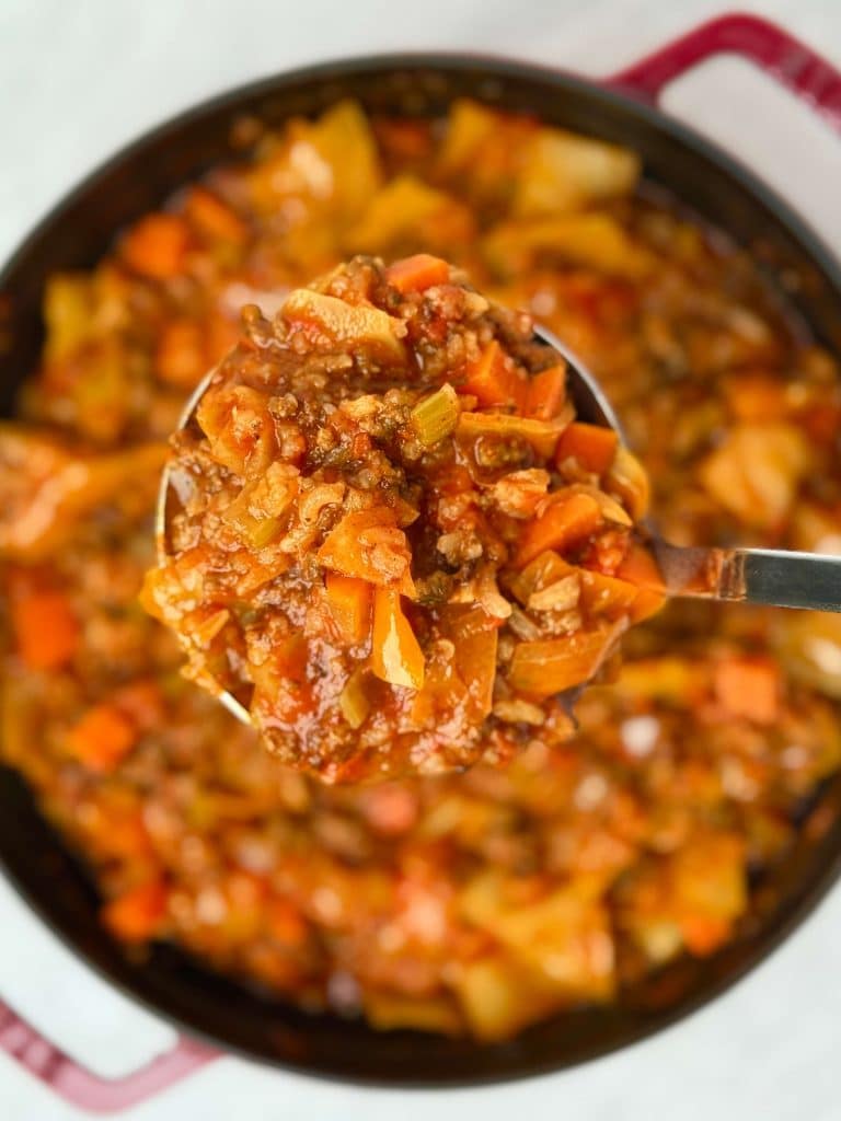Spoonful of unstuffed cabbage soup showing ground beef, cabbage, carrots, and tomato broth