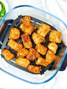 Crispy chili-lime fish cubes in an air fryer basket after cooking
