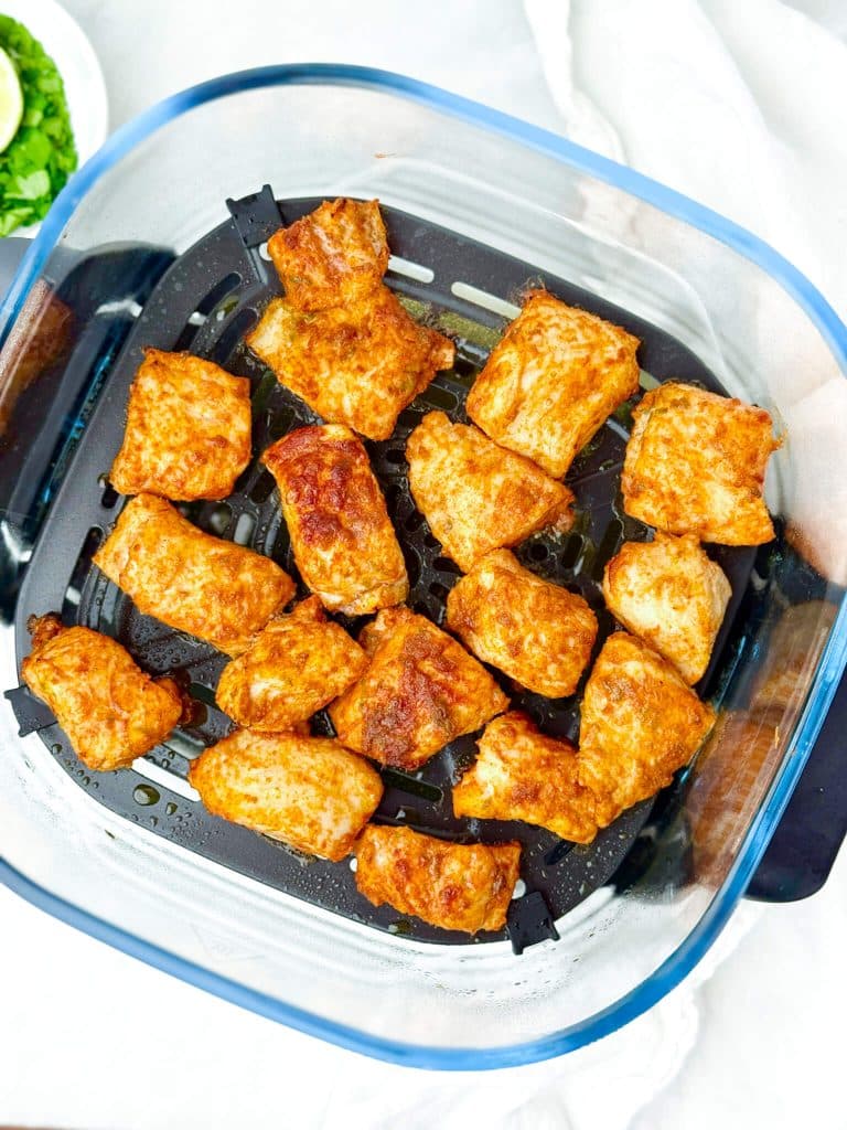 Crispy chili-lime fish cubes in an air fryer basket after cooking