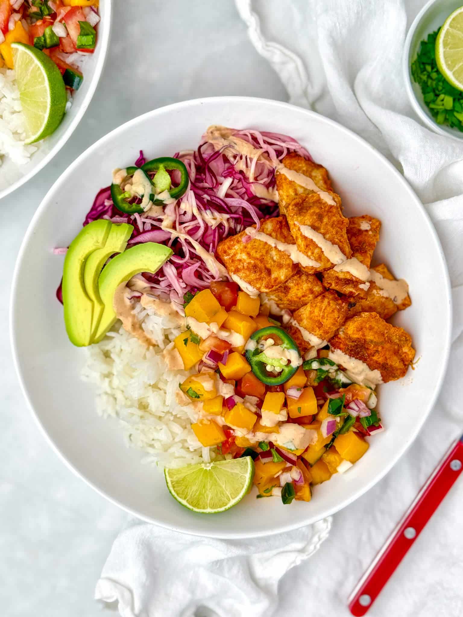 Air fryer fish taco bowl with flaky white fish, mango salsa, black beans, and lime crema over rice