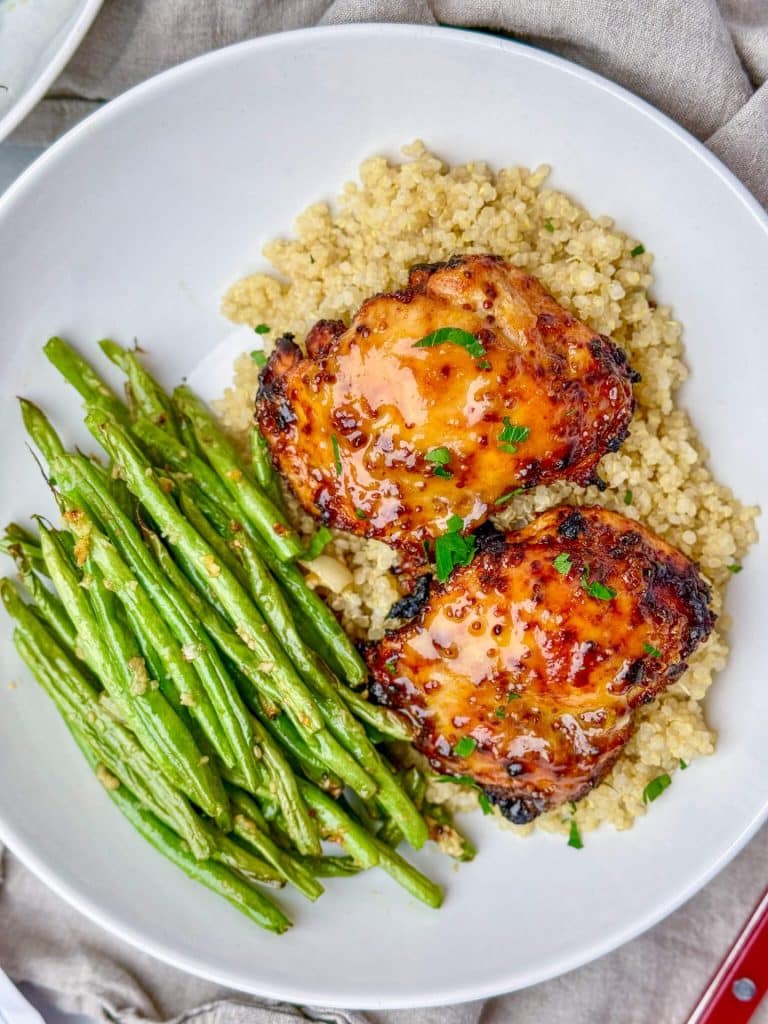 Air fryer honey mustard chicken thighs served over quinoa with garlicky green beans overhead view