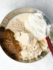 Mixing bowl with oats, protein powder, Greek yogurt, and almond butter before stirring