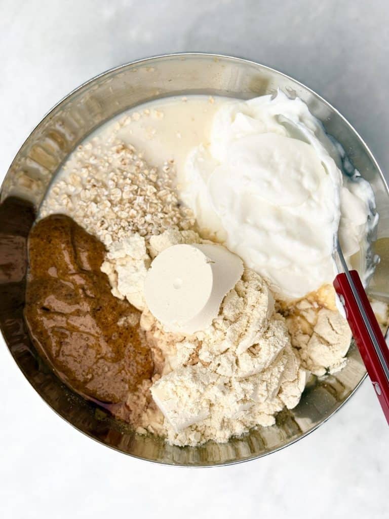 Mixing bowl with oats, protein powder, Greek yogurt, and almond butter before stirring