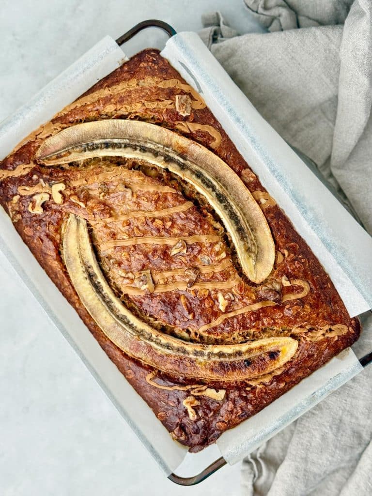 Freshly baked banana bread oatmeal in a baking dish with caramelized banana halves on top
