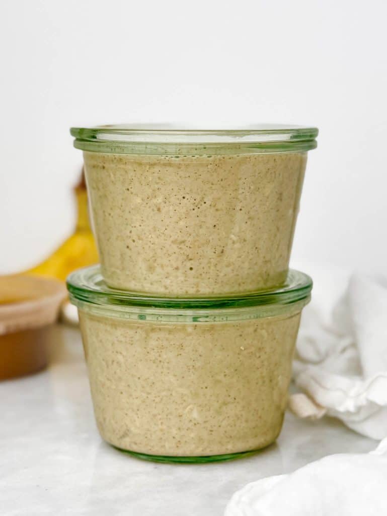 two glass weck jars filled with banana bread overnight oats mixture stacked and sealed with lids ready to refrigerate overnight