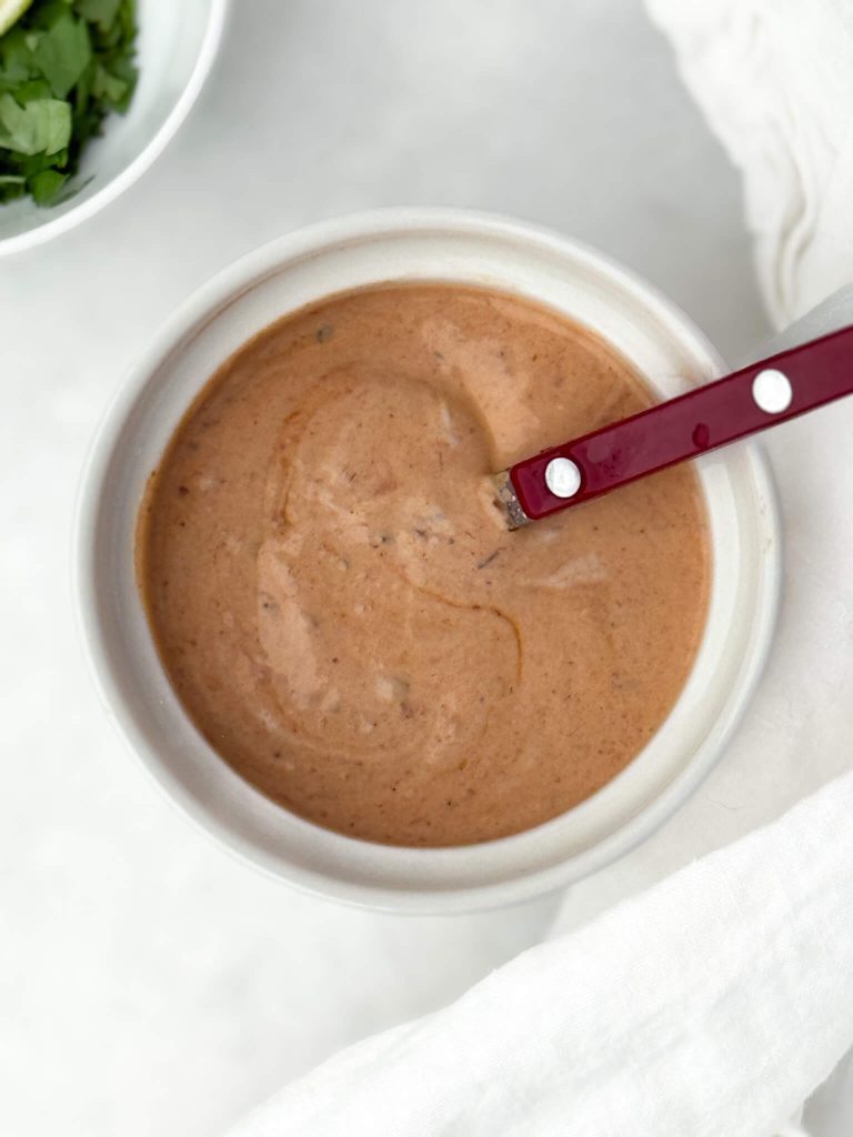 Smoky chipotle crema in a small white bowl with a red spoon