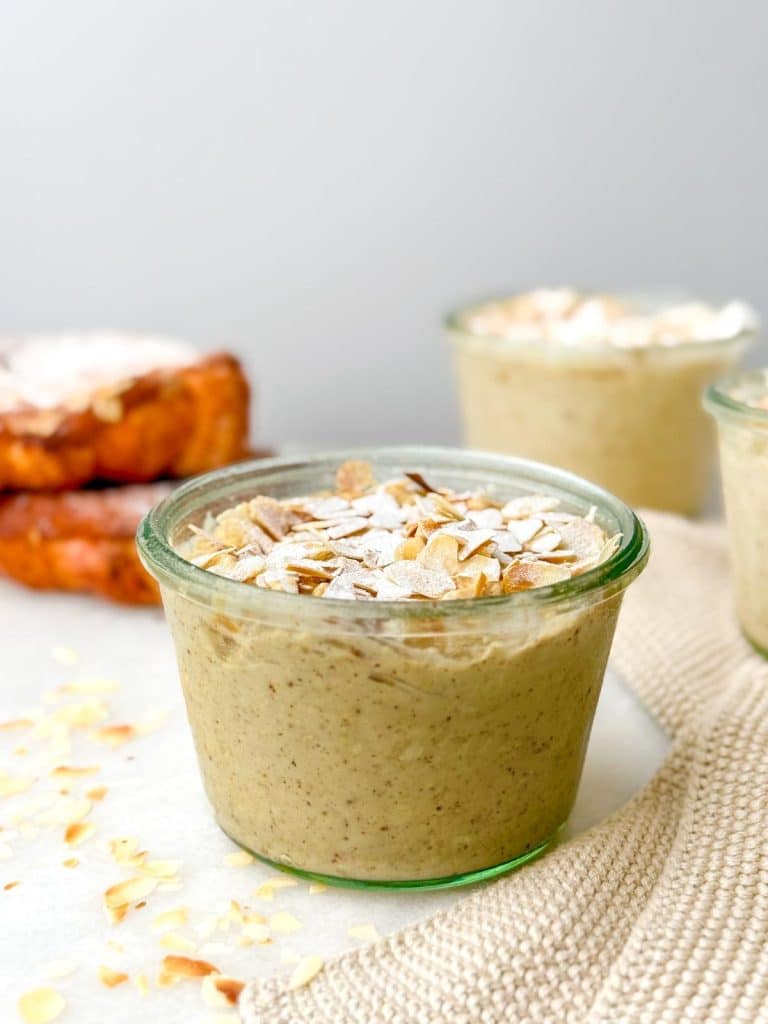 Single glass jar of croissant-flavored overnight oats with sliced almonds on top