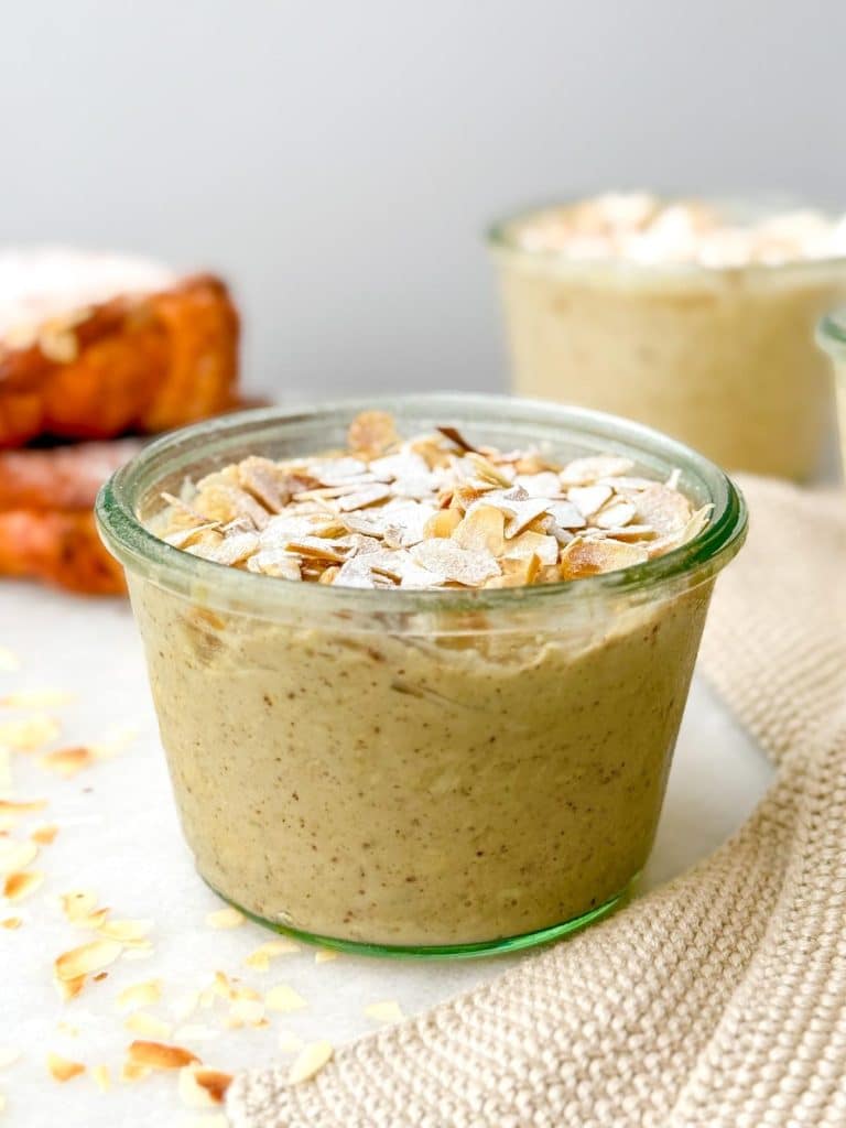 Glass jar of almond croissant overnight oats with toasted coconut and almond flakes