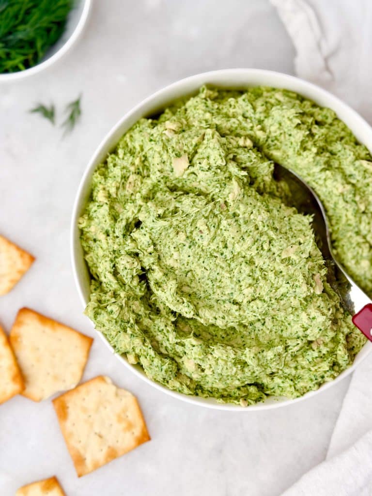 Green goddess chicken salad in a white serving bowl with a red-handled spoon and crackers