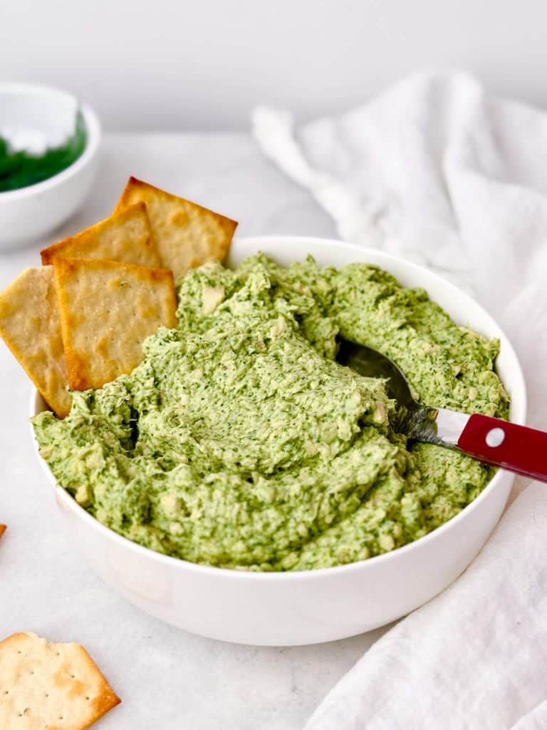Green goddess chicken salad served in a white bowl with pita crackers tucked into the side