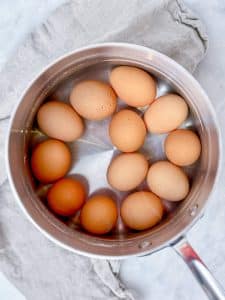12 large brown eggs in a stainless steel pot of water to medium boil for avocado egg salad