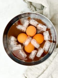 Soft-boiled eggs cooling in an ice bath with ice cubes