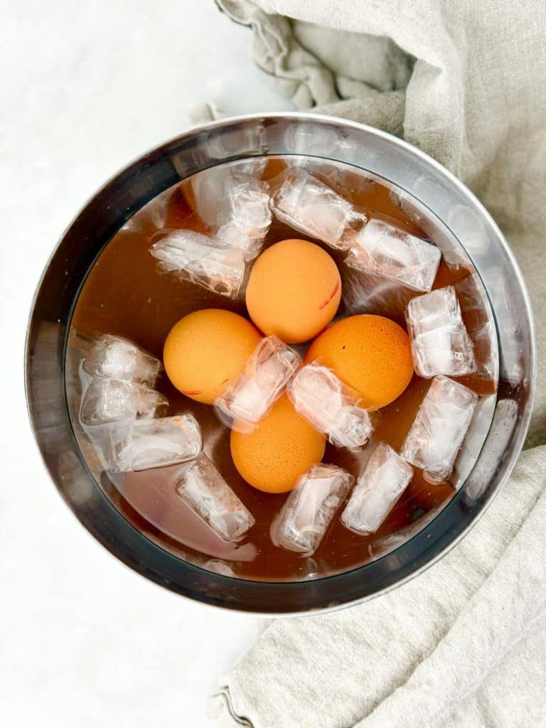 Soft-boiled eggs cooling in an ice bath with ice cubes