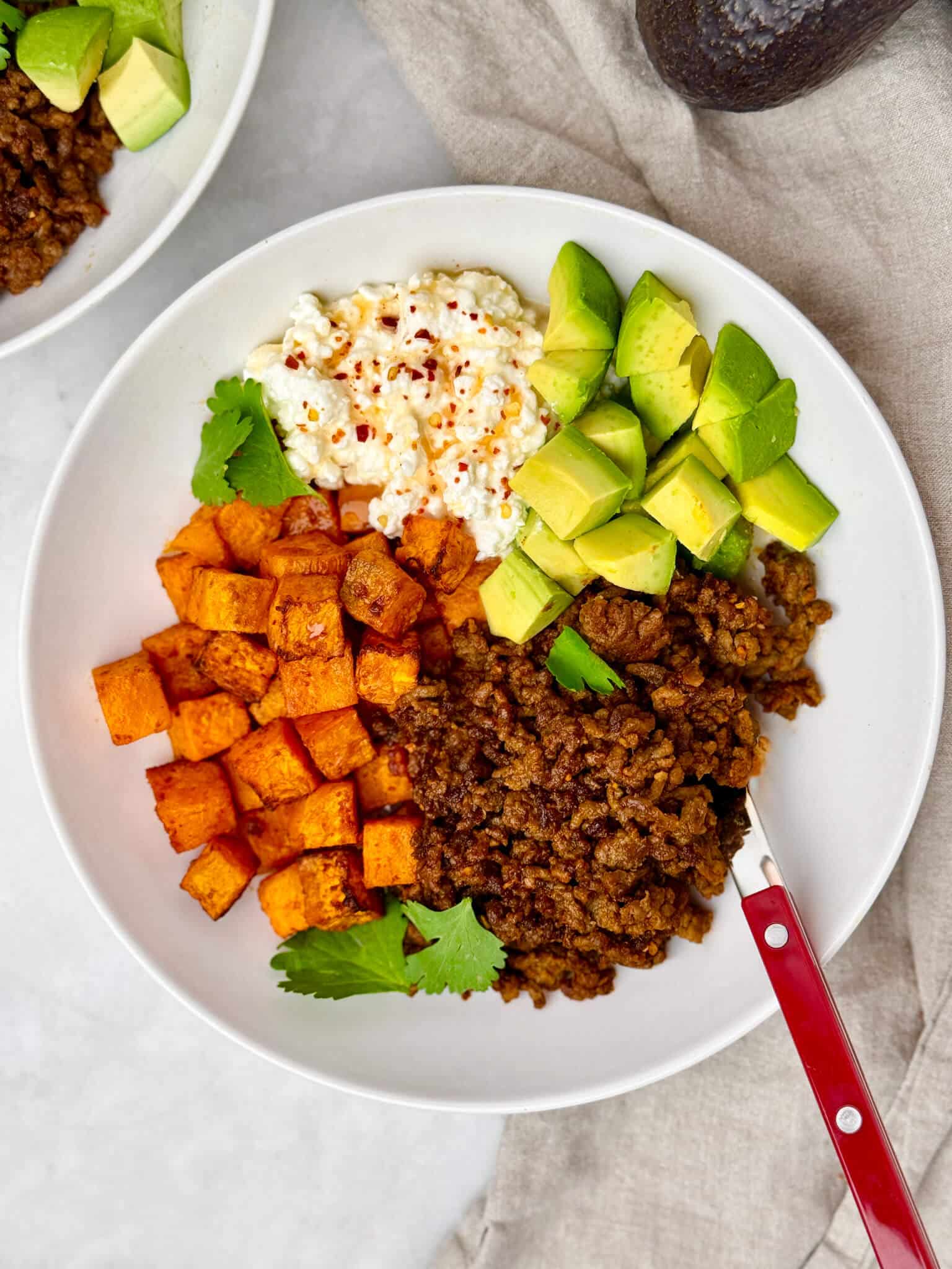 Viral high protein taco bowl with roasted sweet potato, taco beef, cottage cheese, avocado, and cilantro overhead view