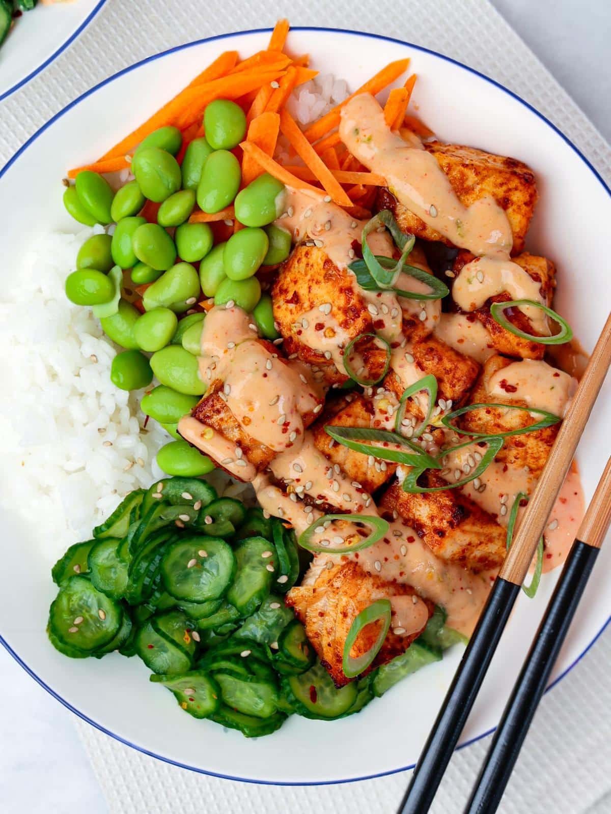 Air fryer salmon bowl with creamy bang bang sauce over rice and veggies