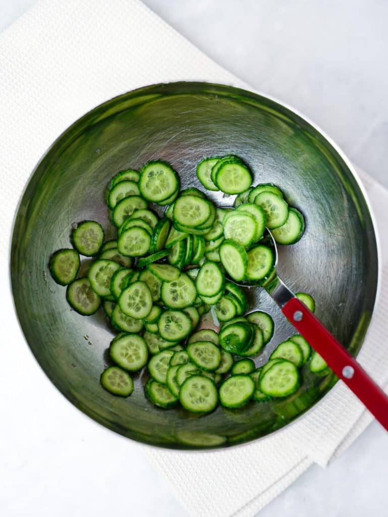Thin-sliced cucumbers in a steel bowl for bang bang salmon bowls