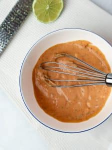 Creamy bang bang sauce whisked in a bowl with fresh lime