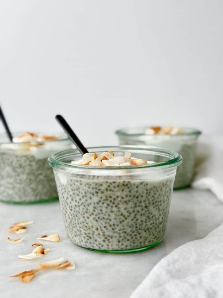 Coconut chia pudding meal prep jars with scattered toasted coconut flakes
