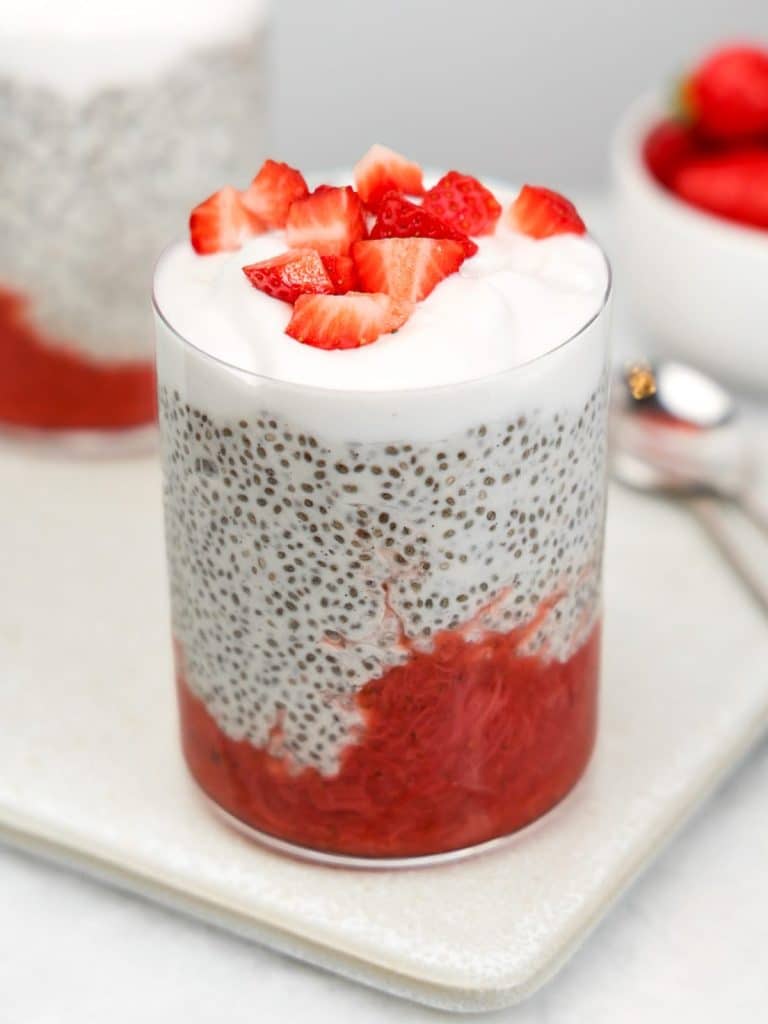 Chia pudding with strawberry rhubarb jam in a glass topped with diced strawberries