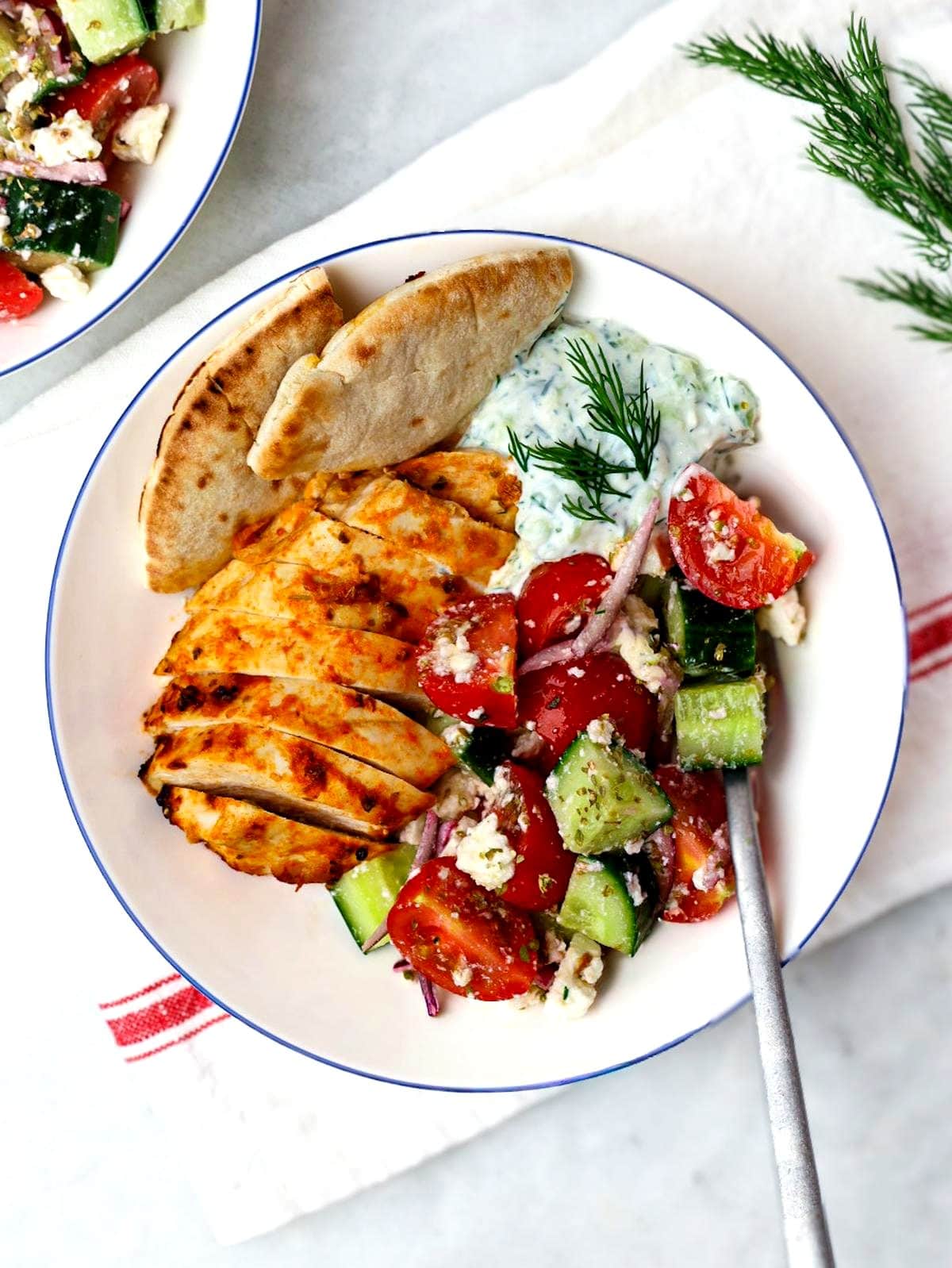 Overhead chicken tzatziki bowl with sliced chicken, tzatziki sauce, and warm pita