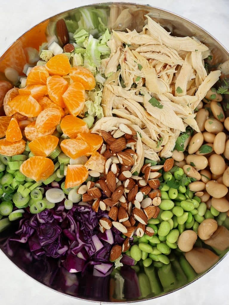 Single bowl of dense bean salad with chicken topped with sesame seeds and scallions