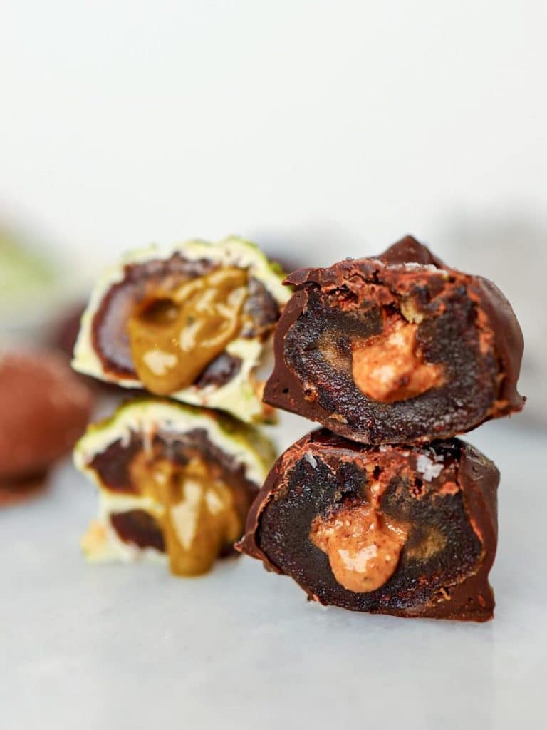 Cross section of three chocolate dipped stuffed dates showing nut butter inside