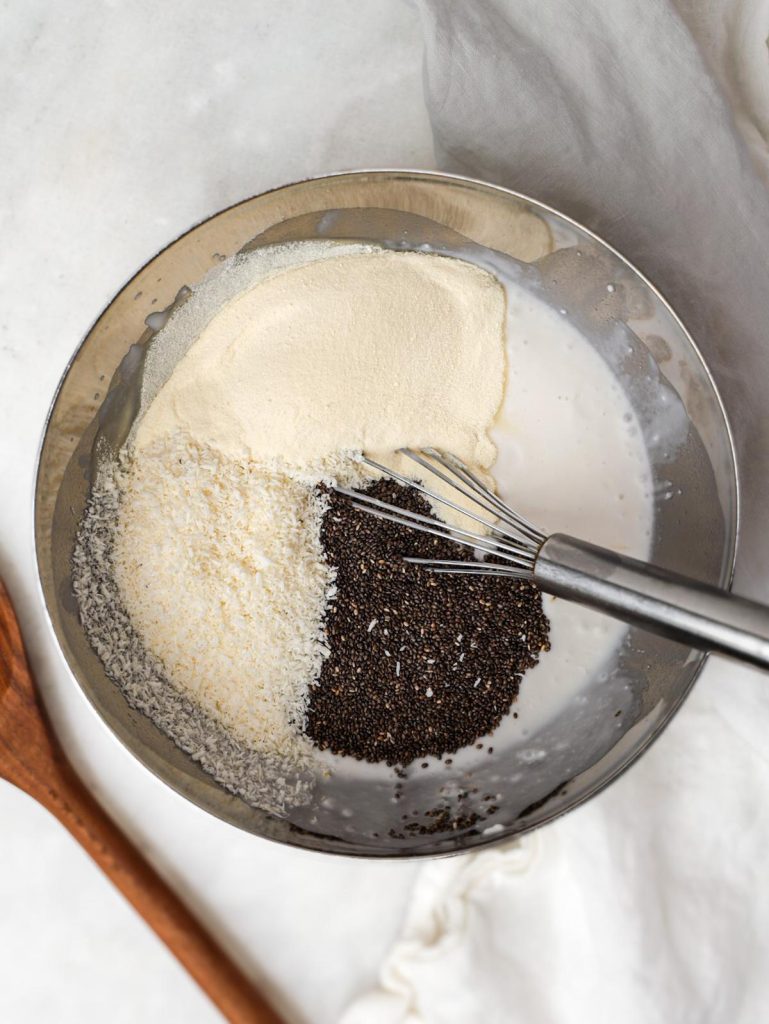 Chia seeds shredded coconut and protein powder in a bowl with coconut milk before mixing