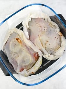 Two sealed parchment parcels with Mediterranean cod ready for the air fryer