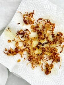 Crispy fried shallots draining on a paper towel