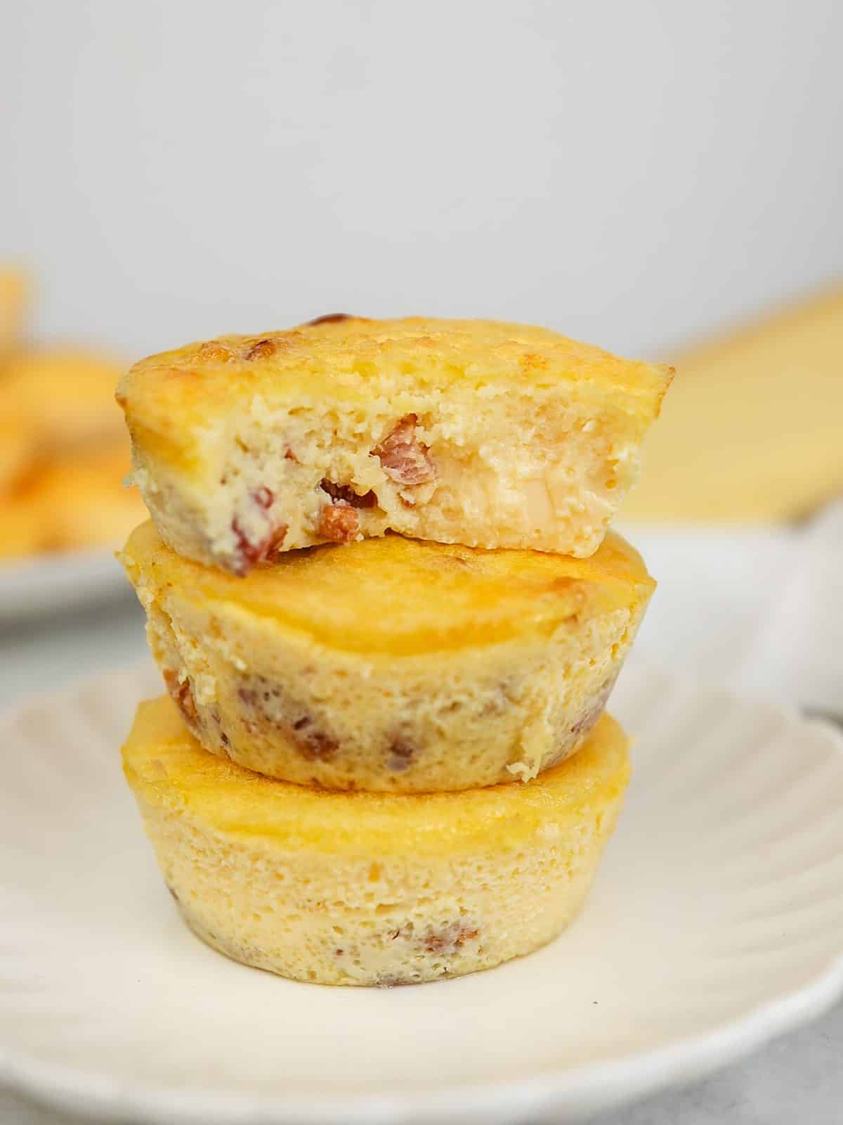Stack of three quiche lorraine egg bites with a bite taken out of the top one