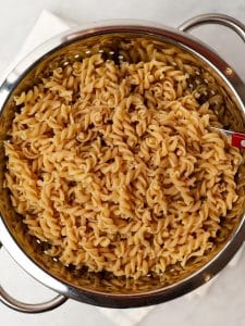 Cooked high-protein rotini pasta draining in a colander for easy Mediterranean pasta salad