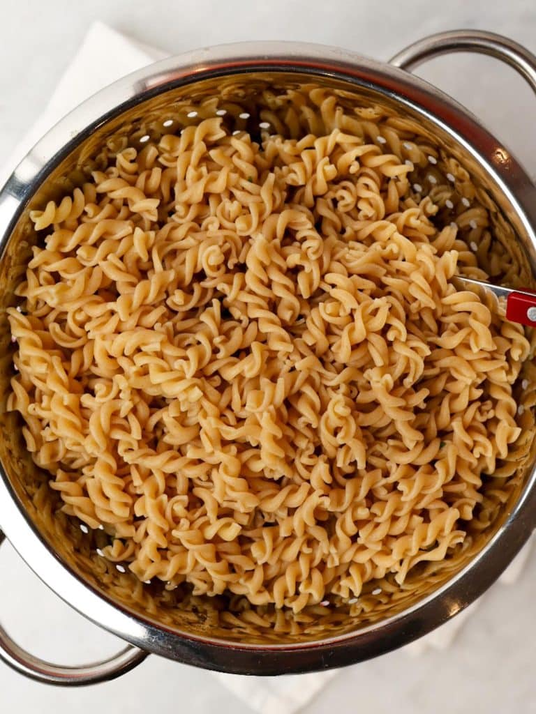 Cooked high-protein rotini pasta draining in a colander for easy Mediterranean pasta salad