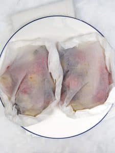 Two sealed parchment parcels with Mediterranean cod ready for the air fryer