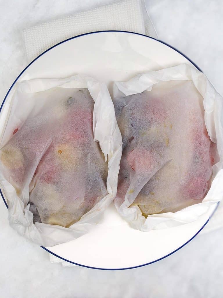 Two sealed parchment parcels with Mediterranean cod ready for the air fryer