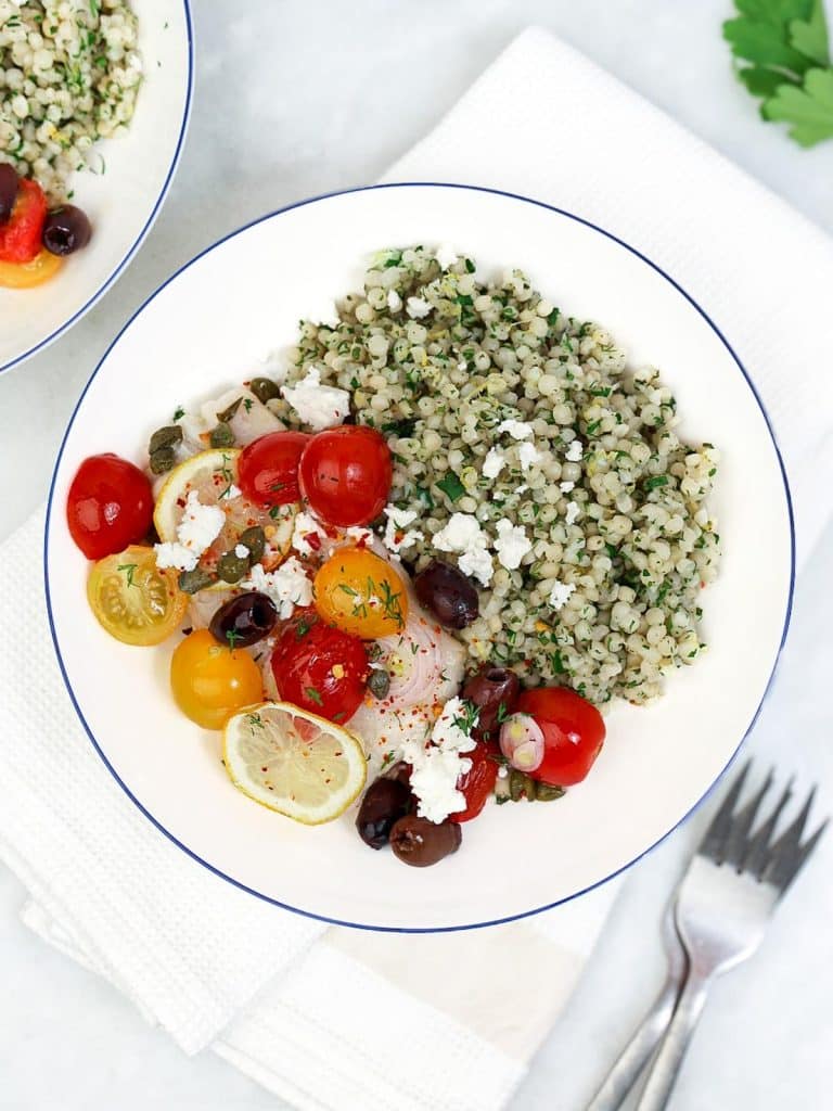 Bowl of Mediterranean cod with herby israeli couscous, kalamata olives, cherry tomatoes, and feta