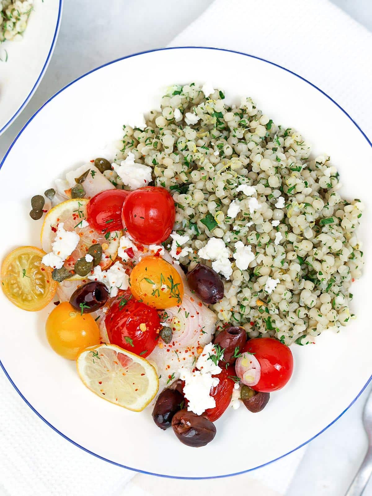Open parchment parcel of Mediterranean cod with cherry tomatoes, kalamata olives, capers, and lemon slices