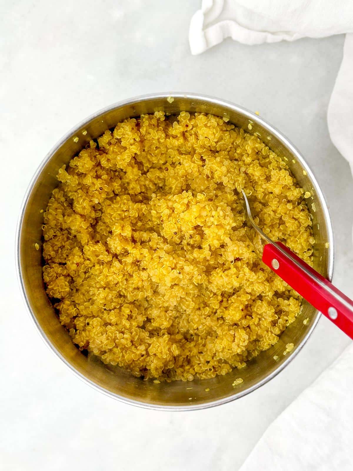 Golden turmeric quinoa in a saucepan with a red spoon