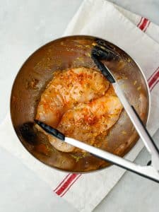 Chicken breast marinating in lemon oregano and olive oil in a mixing bowl