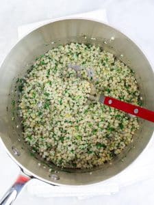 Pot of cooked israeli couscous tossed with fresh dill, parsley, mint, and lemon zest