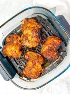 Caramelized hot honey chicken thighs in an air fryer basket