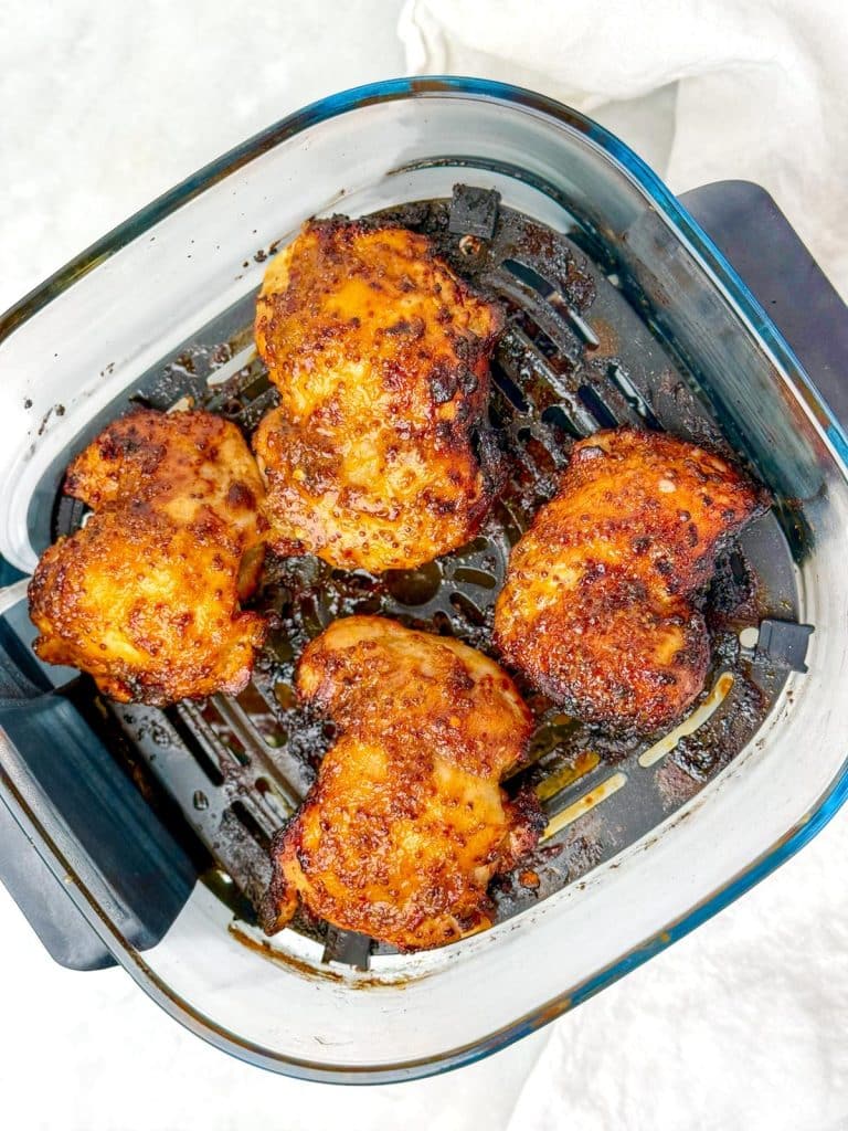 Caramelized hot honey chicken thighs in an air fryer basket