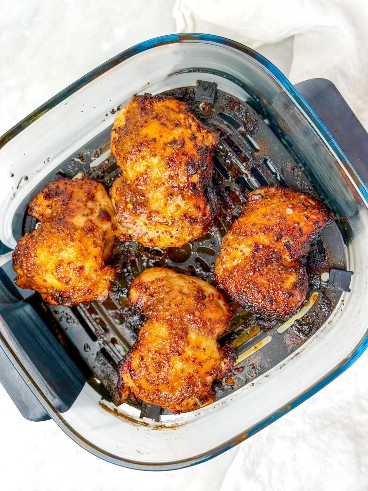 Caramelized hot honey chicken thighs in an air fryer basket