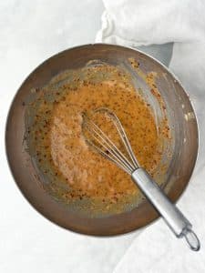 Hot honey mustard sauce with whole grain mustard whisked in a bowl