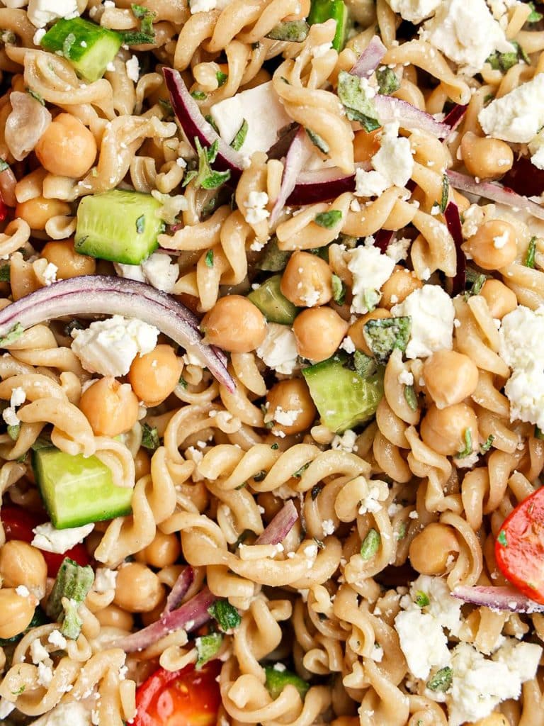 Close-up of Mediterranean pasta salad with chickpeas, crumbled feta, cucumber, red onion, and rotini
