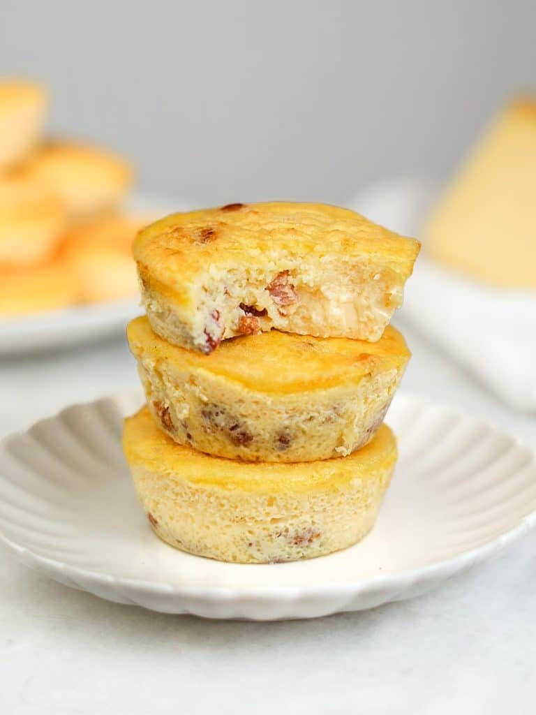 Close-up stack of crustless quiche lorraine egg bites showing crispy lardons and creamy cheese inside